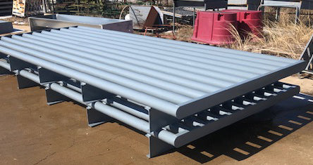 Two gray, round top rail cattle guards stacked on top of one another.