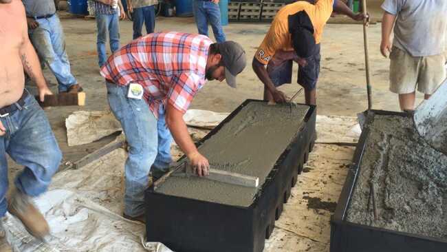 Workers leveling the cement in a concrete cattle guard form.