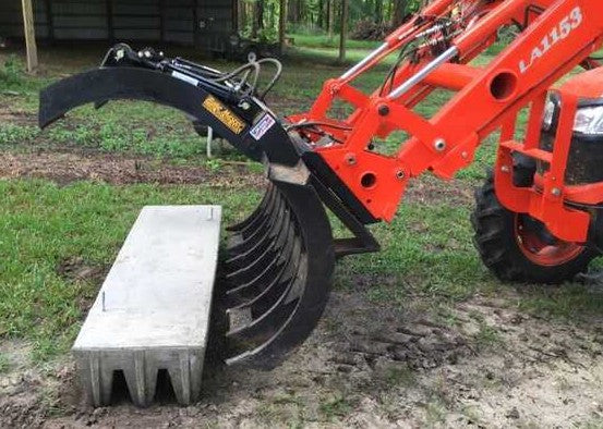 A tractor moving a concrete cattle guard.