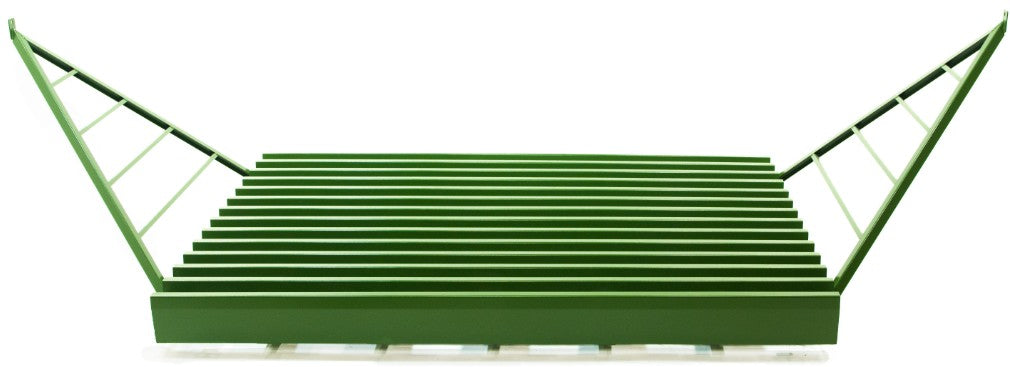 A green cattle guard with large wings attached to connect to a fenceline.