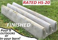 A finished concrete cattle guard resting on the grass.